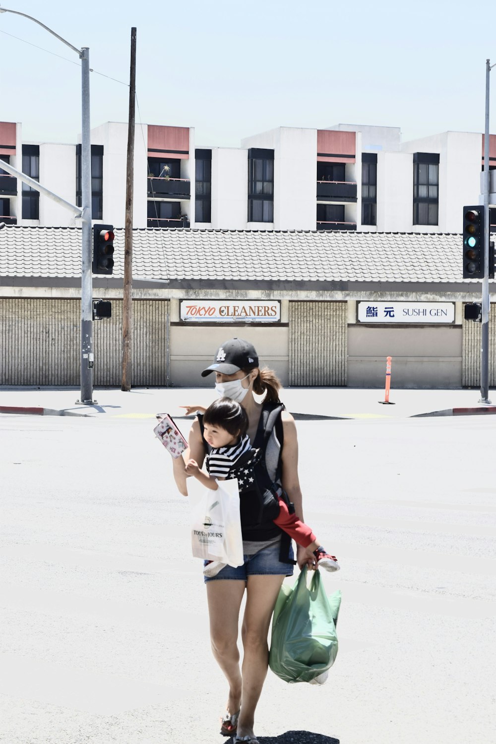 woman in black and white tank top and white shorts carrying green plastic bag