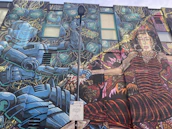 Vibrant comic-style drawing of a cheerful robot mascot waving hello in a colorful workshop.