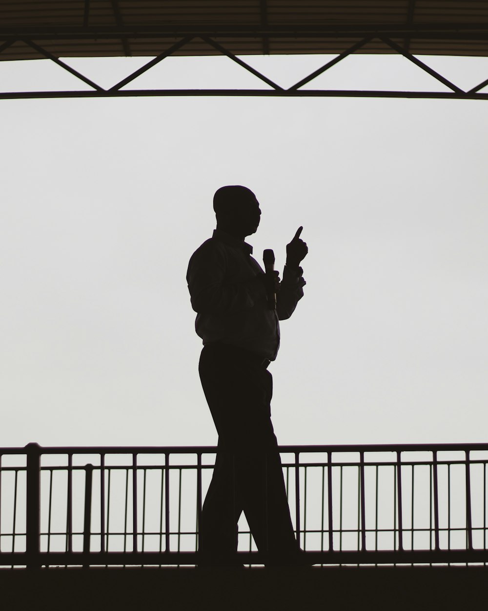 silhouette of man standing near fence during daytime