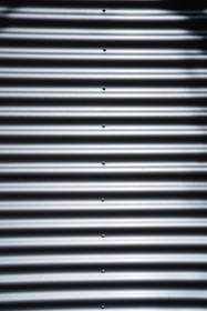 Corrugated metal sheet with horizontal ridges and bolts aligned vertically in the center.