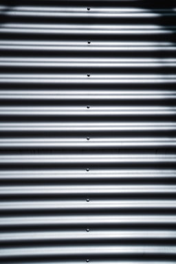 Corrugated metal sheet with horizontal ridges and bolts aligned vertically in the center.