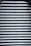 Corrugated metal sheet with horizontal ridges and bolts aligned vertically in the center.