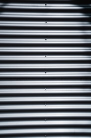 Corrugated metal sheet with horizontal ridges and bolts aligned vertically in the center.