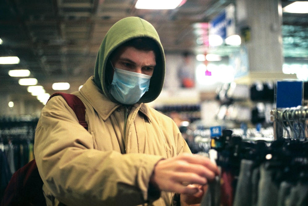 man in green hoodie and green mask holding black dslr camera