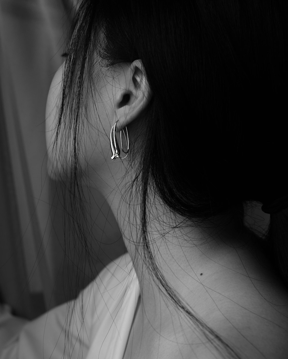woman with silver earring grayscale photo