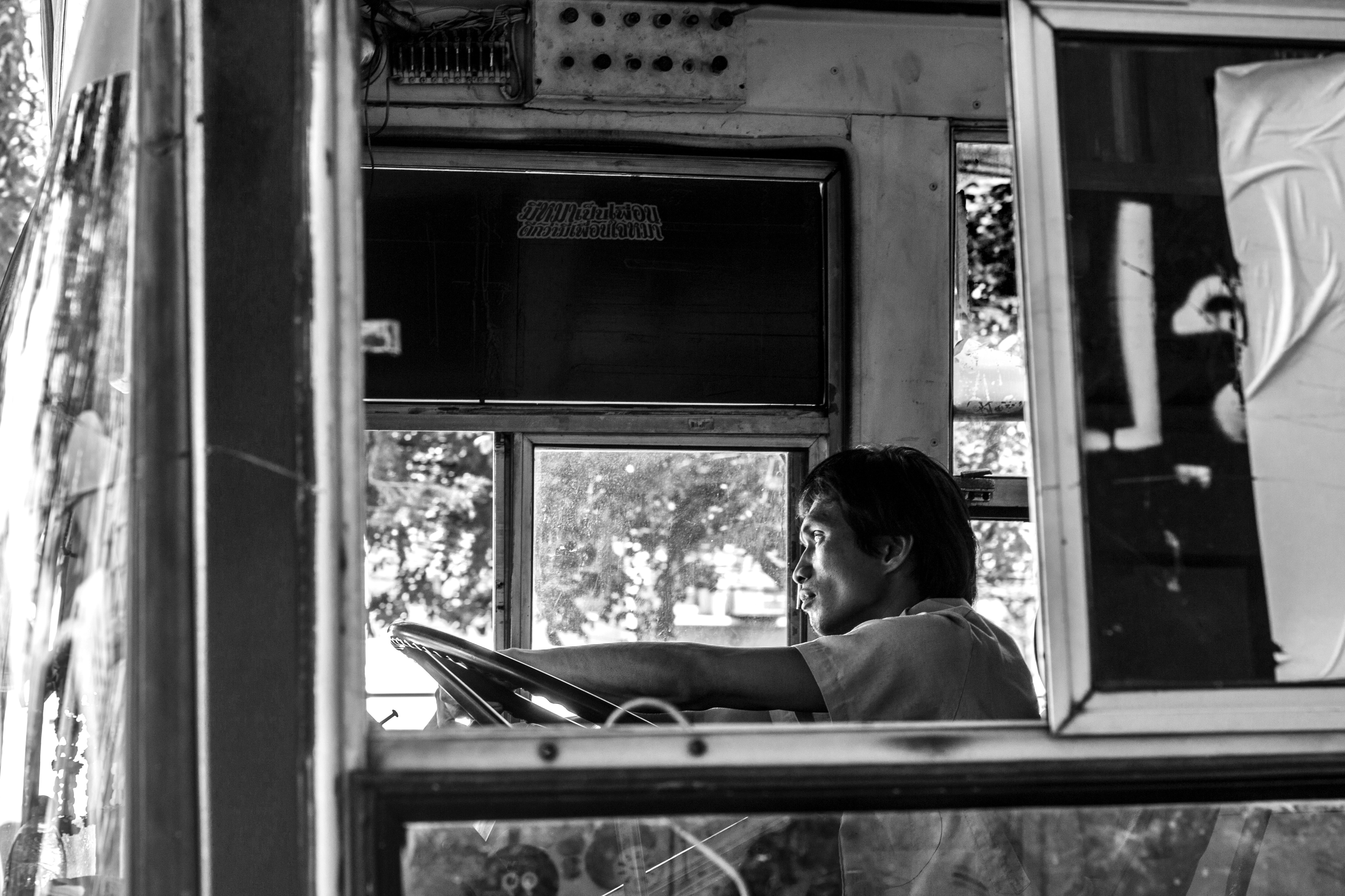grayscale photo of man sitting on car seat