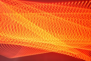 LED lights captured with a slow shutter speed, creating geometric and intricate fiery-orange lines.