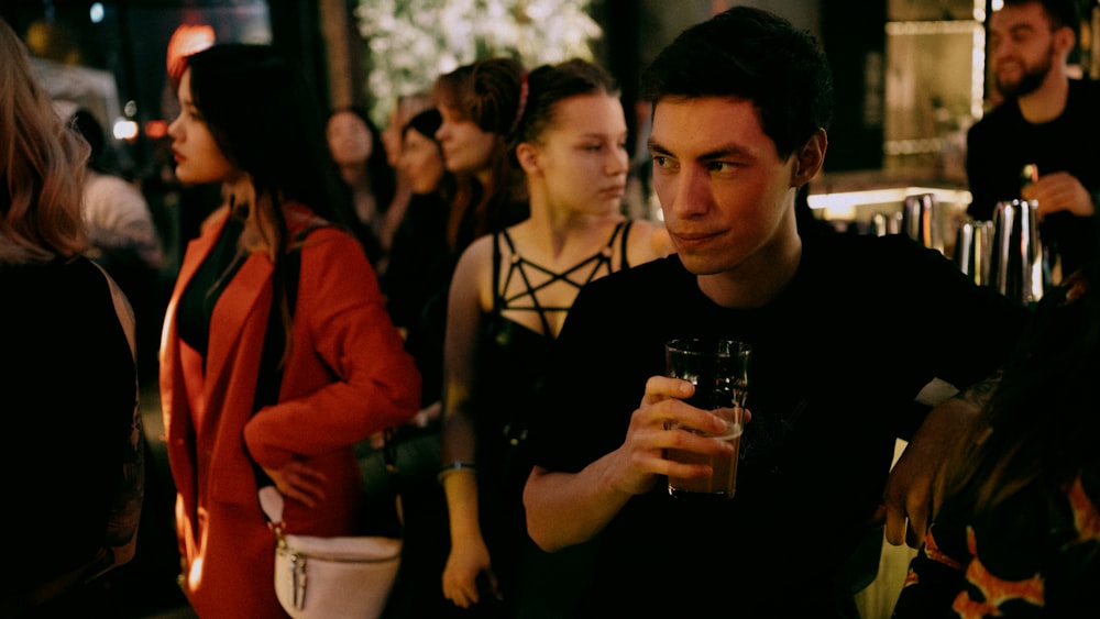 man in black tank top holding drinking glass