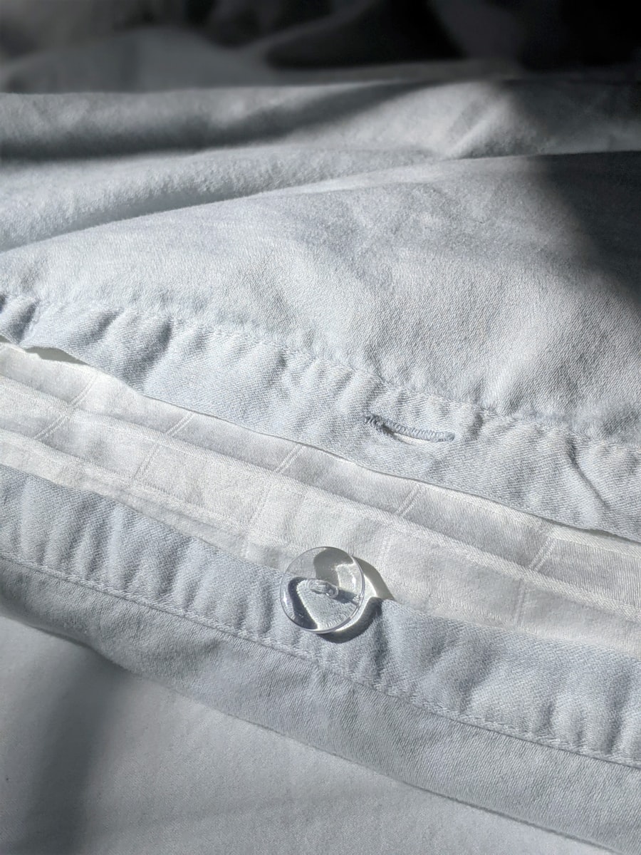 Close-up of percale fabric seam and hem stitching during quality inspection