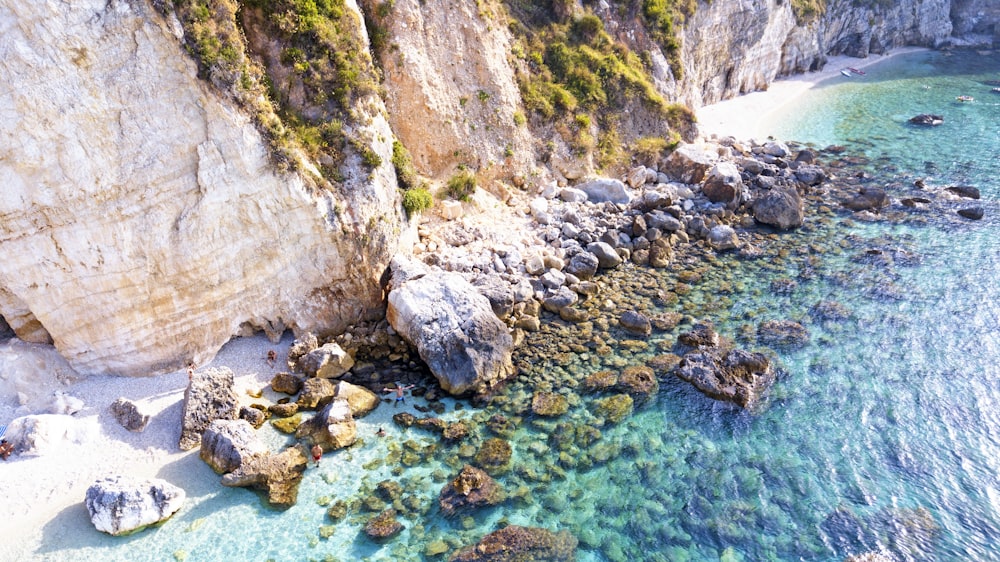 brown rocky mountain beside blue sea during daytime