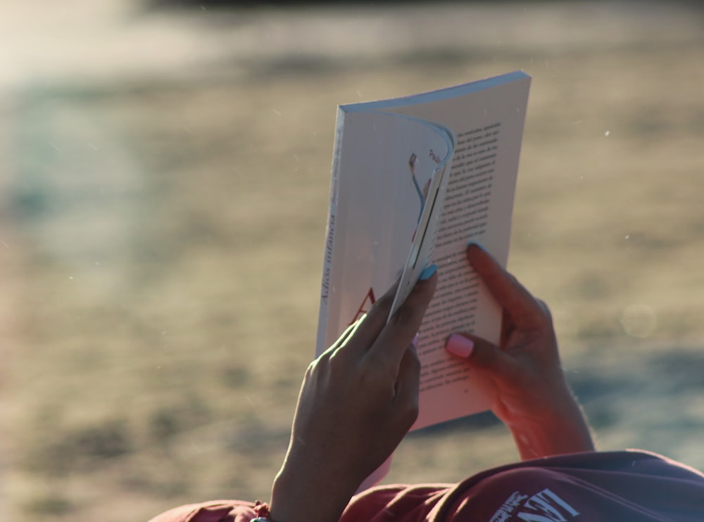 person holding white book during daytime