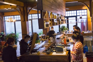 Waiters and bartenders serving customers in a cozy café setting.