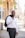 man in white dress shirt and black pants standing on sidewalk during daytime