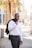 man in white dress shirt and black pants standing on sidewalk during daytime