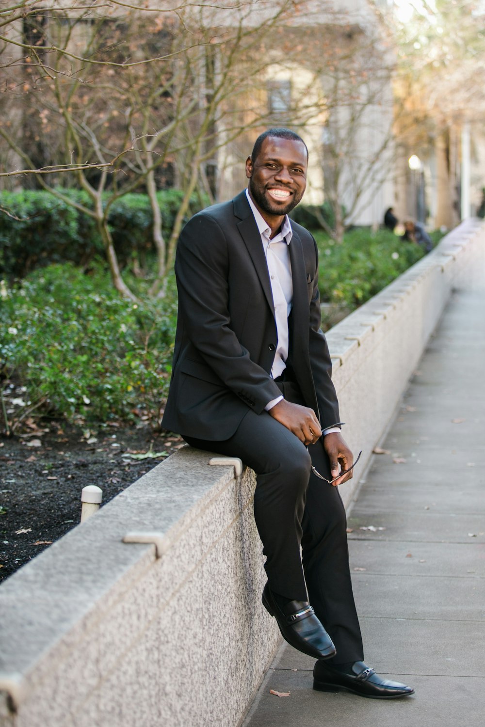 man in black suit jacket and black pants standing on pathway