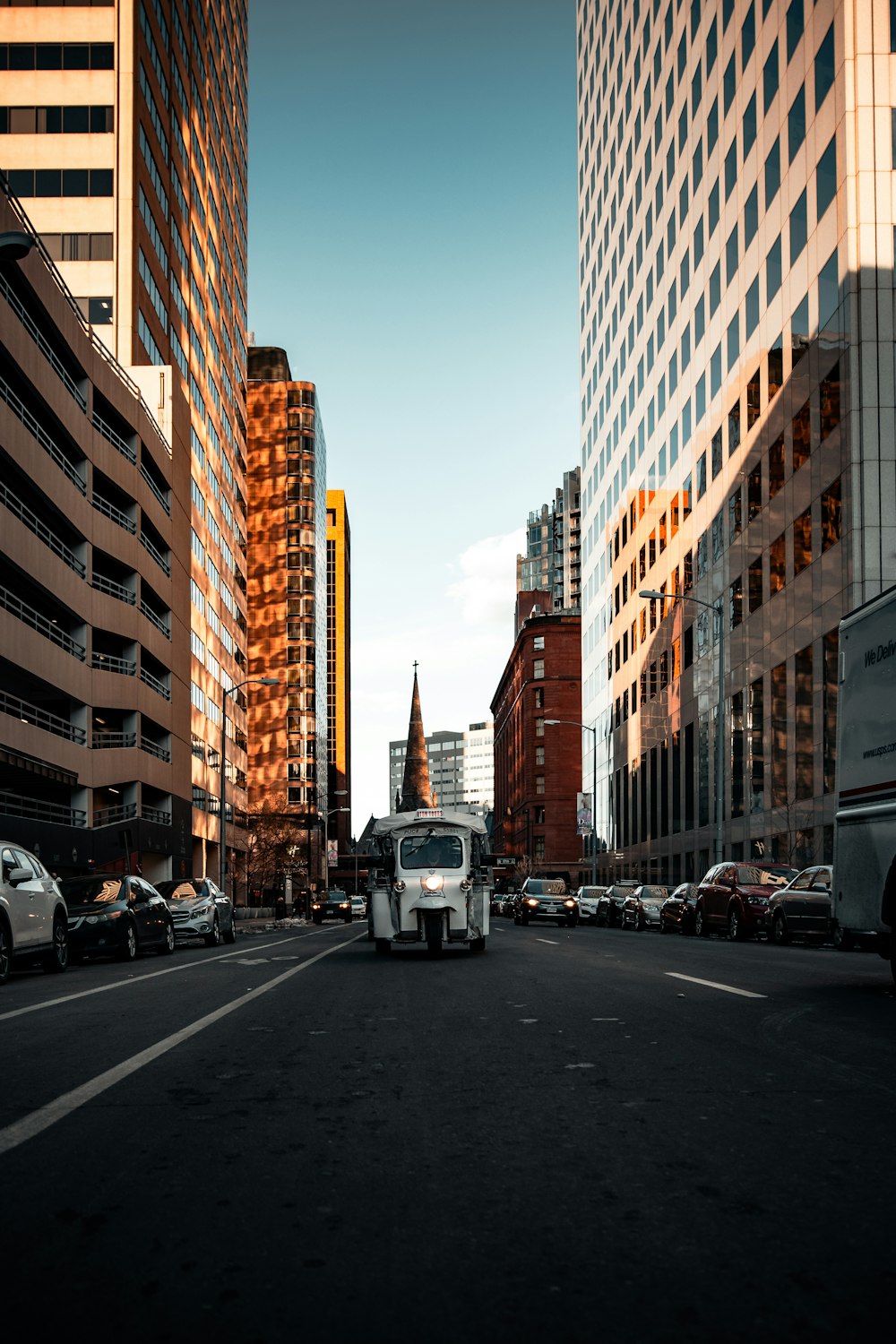 cars on road in between high rise buildings during daytime