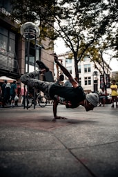 man in black t-shirt and blue denim jeans jumping on street during daytime