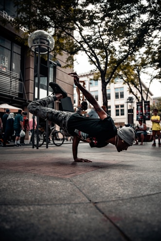 man in black t-shirt and blue denim jeans jumping on street during daytime