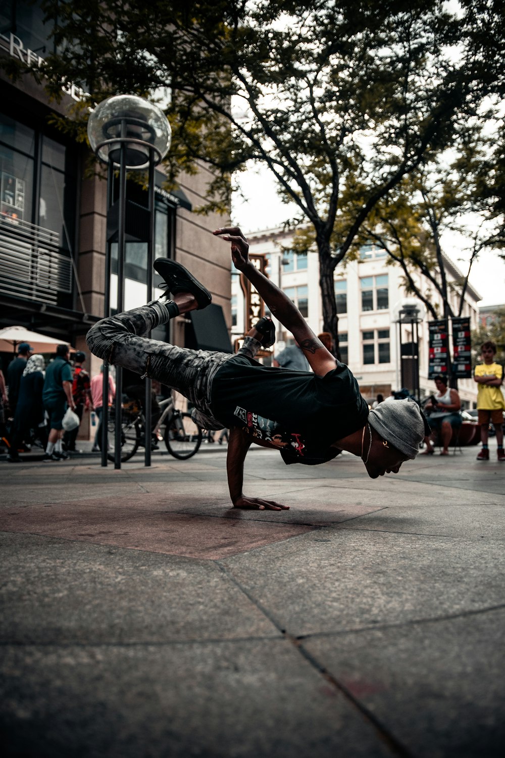 man in black t-shirt and blue denim jeans jumping on street during daytime