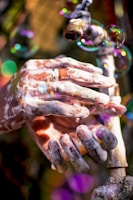 Close-up of hands lathered with soap under running water, highlighting bubbles and cleanliness.