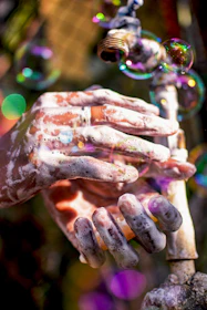 Bubbles rising from dishwashing liquid near a sparkling clean plate and glassware.