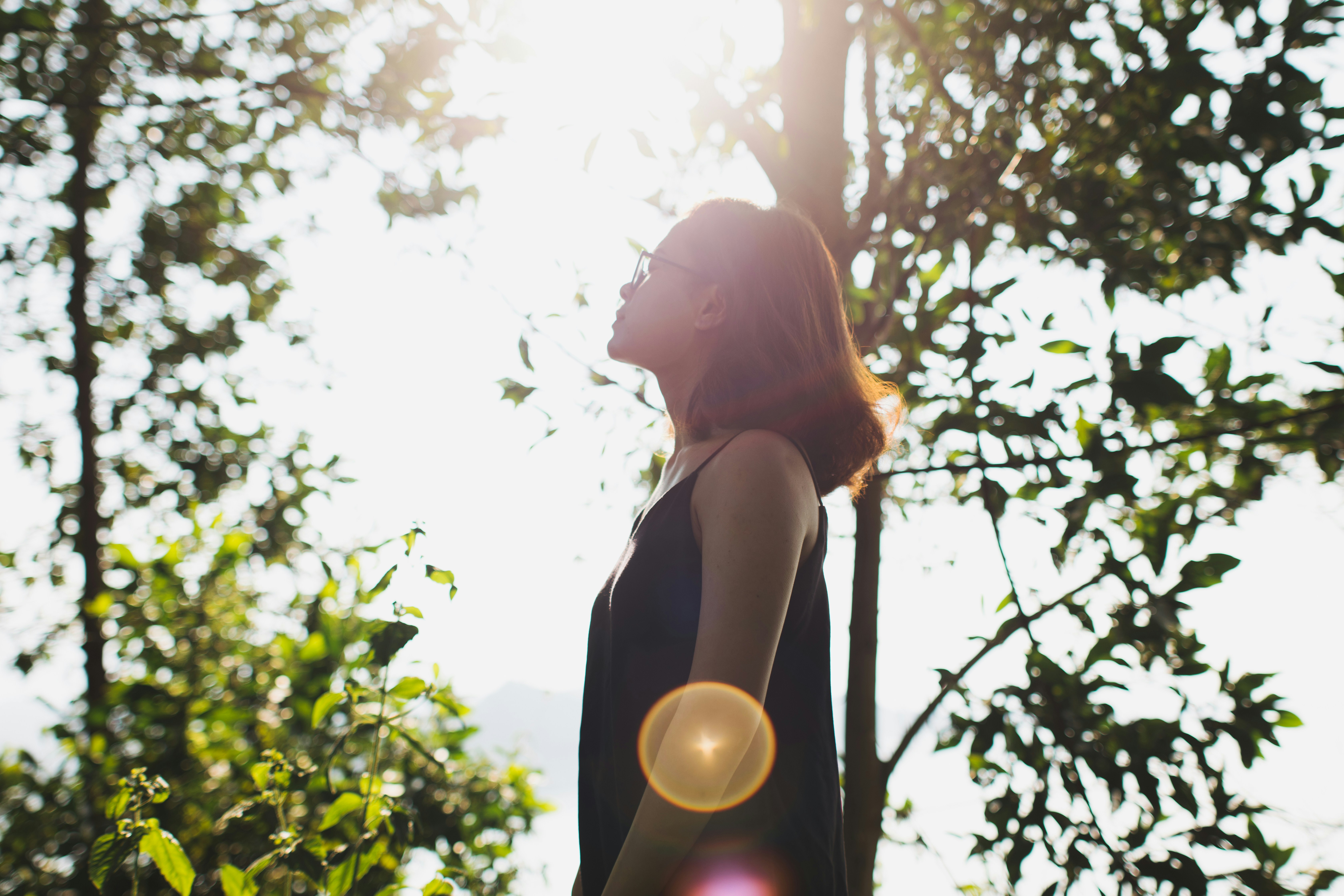 woman in black tank top standing under green tree during daytime