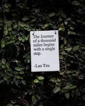 white and black quote board on green plants