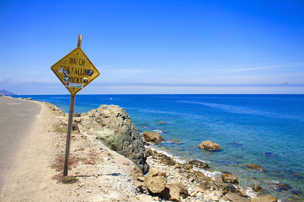 brown and white street sign near body of water during daytime