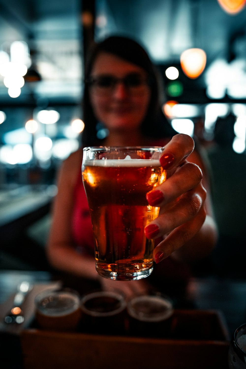 woman holding clear drinking glass with brown liquid