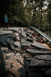 man in blue jacket and blue denim jeans walking on brown wooden bridge during daytime