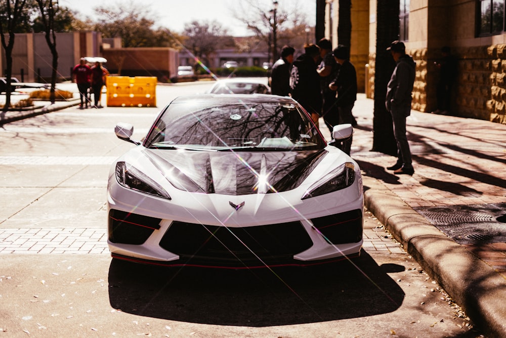 white and black lamborghini aventador parked on sidewalk during daytime