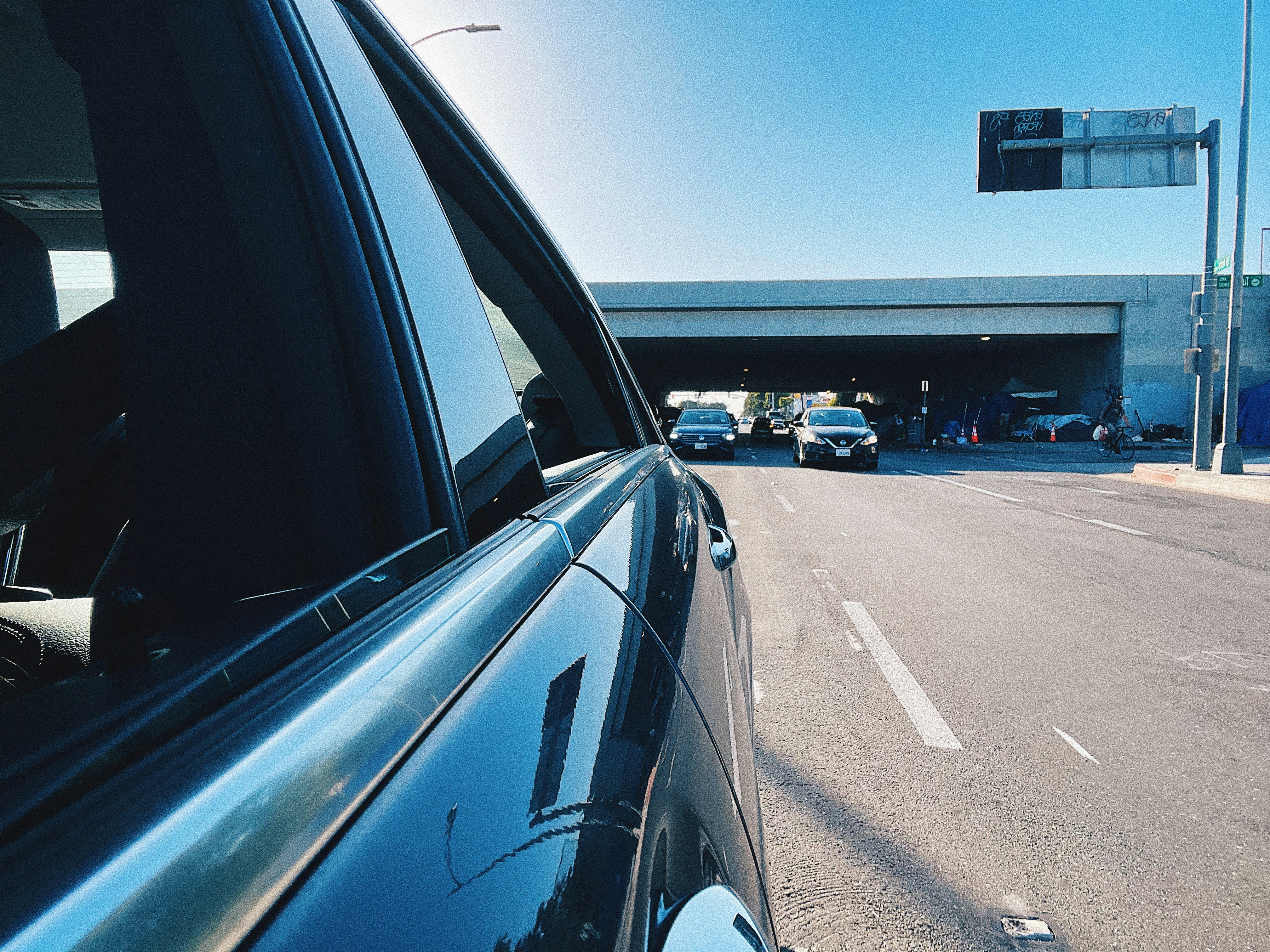 A concerned person looking at car documents with a car in the background.