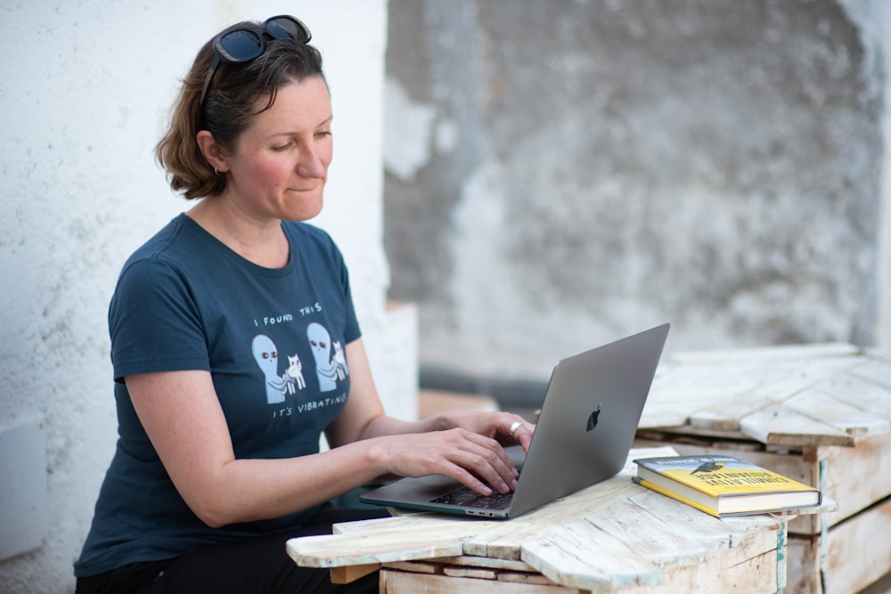 Femme en T-shirt bleu à col rond utilisant MacBook