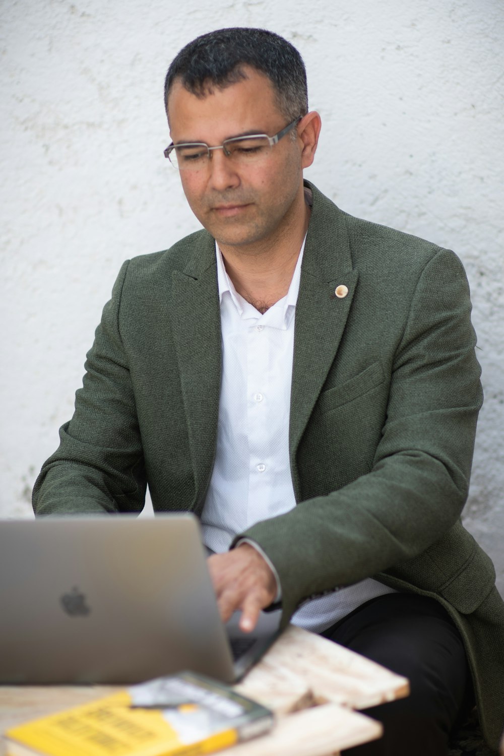 man in gray suit jacket using macbook