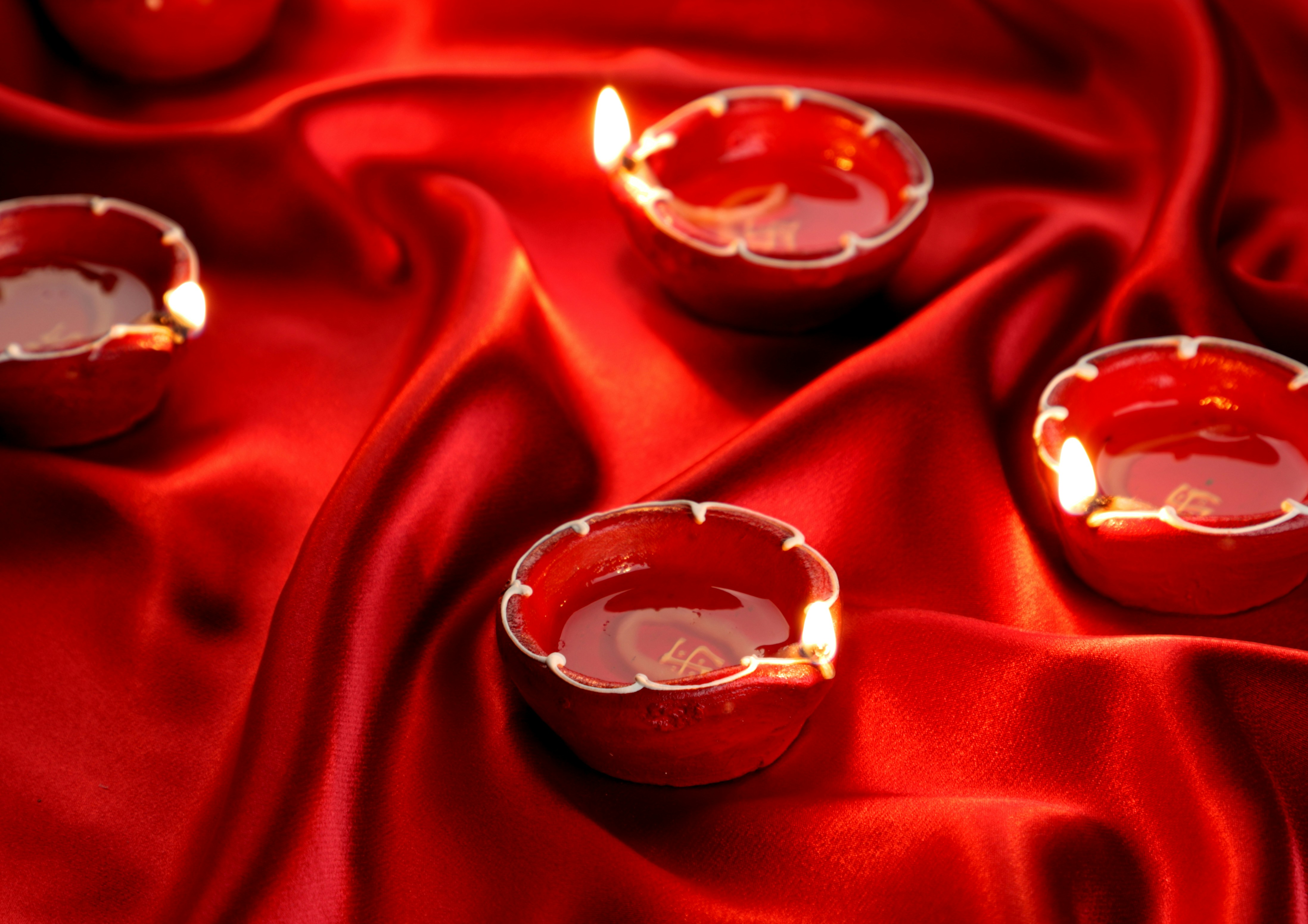 2 clear glass candle holders on red textile, Indian Festival Diwali Diyas on a Red Satin
