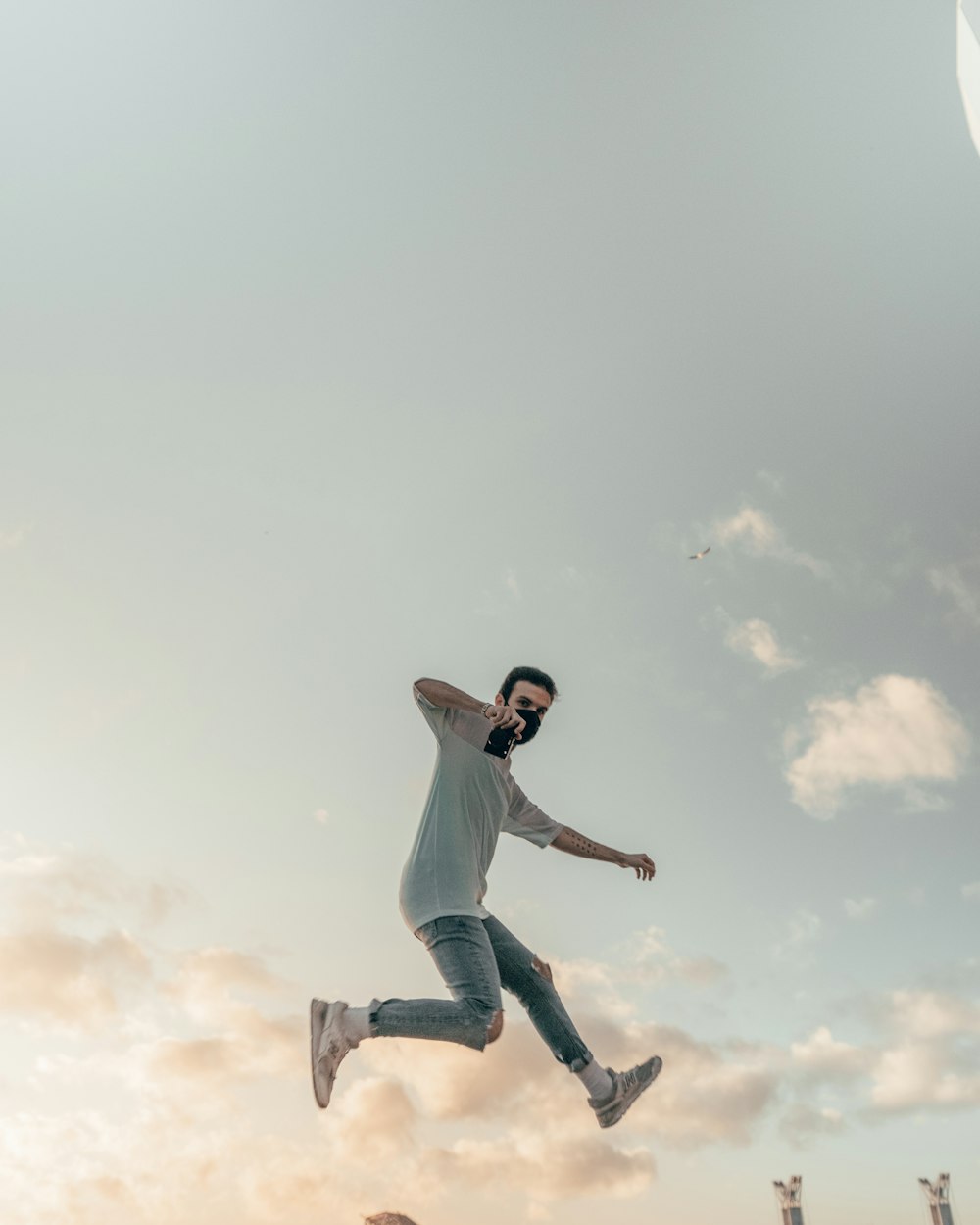 man in white t-shirt and blue denim jeans jumping