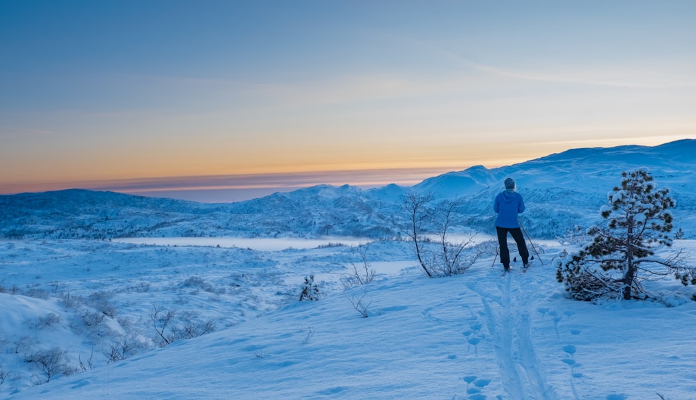 man in black jacket and pants walking on snow covered ground during daytime