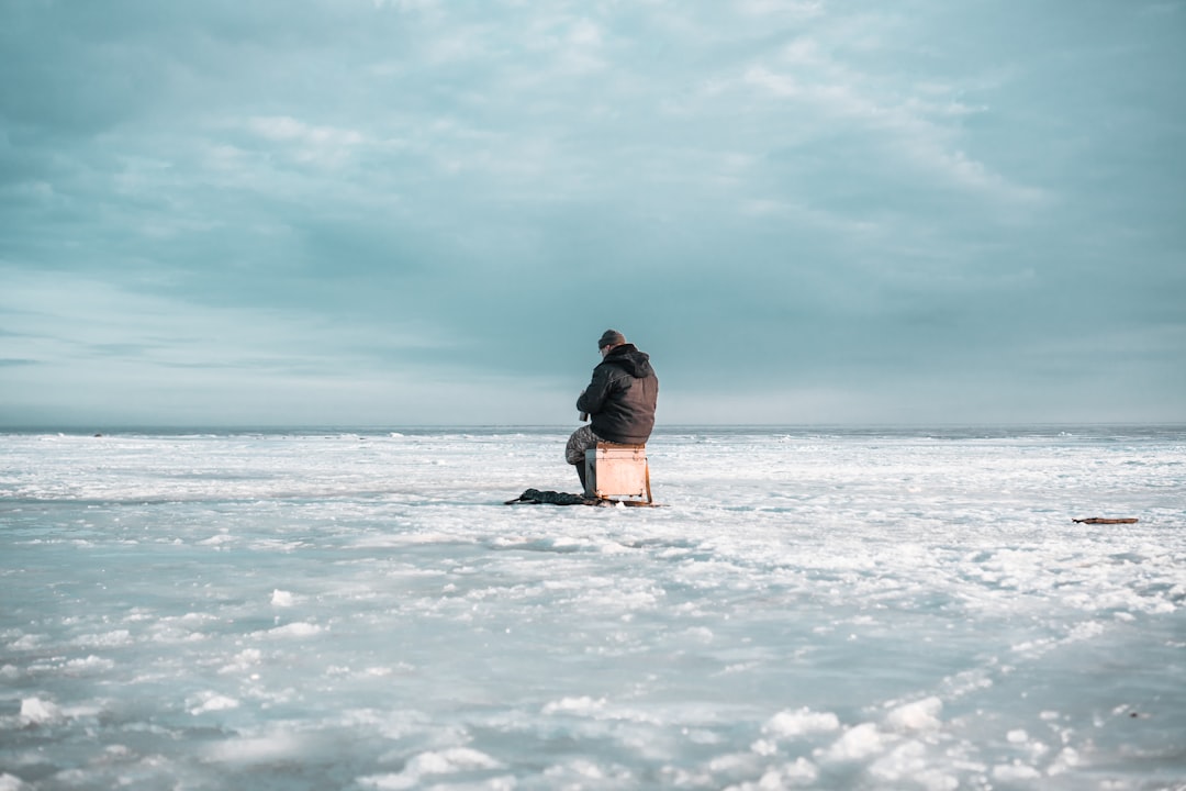 man in brown jacket sitting on snow covered ground during daytime