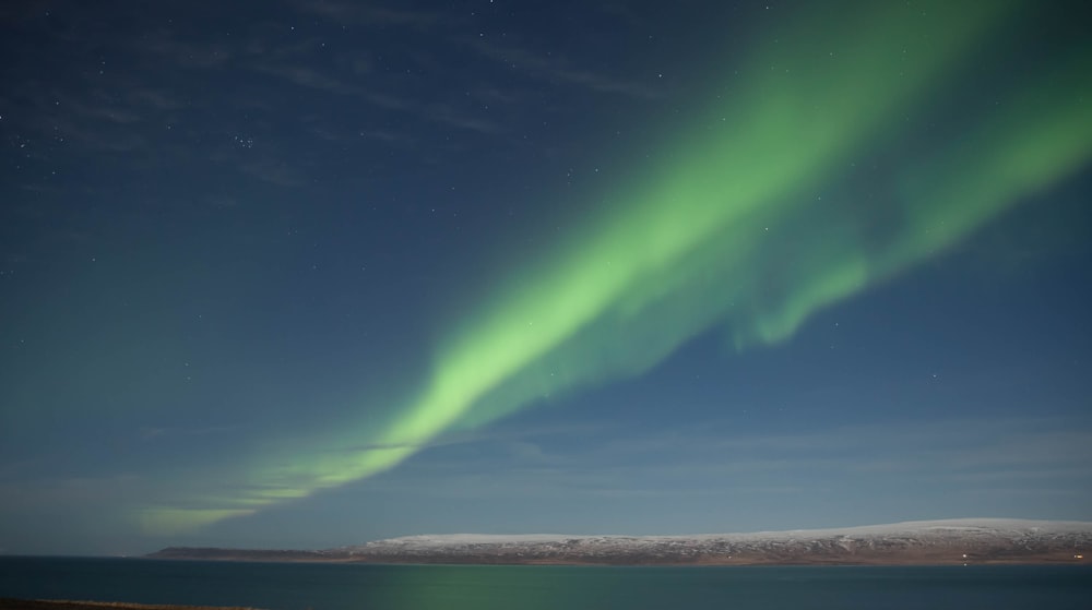 green aurora lights over the sea during night time