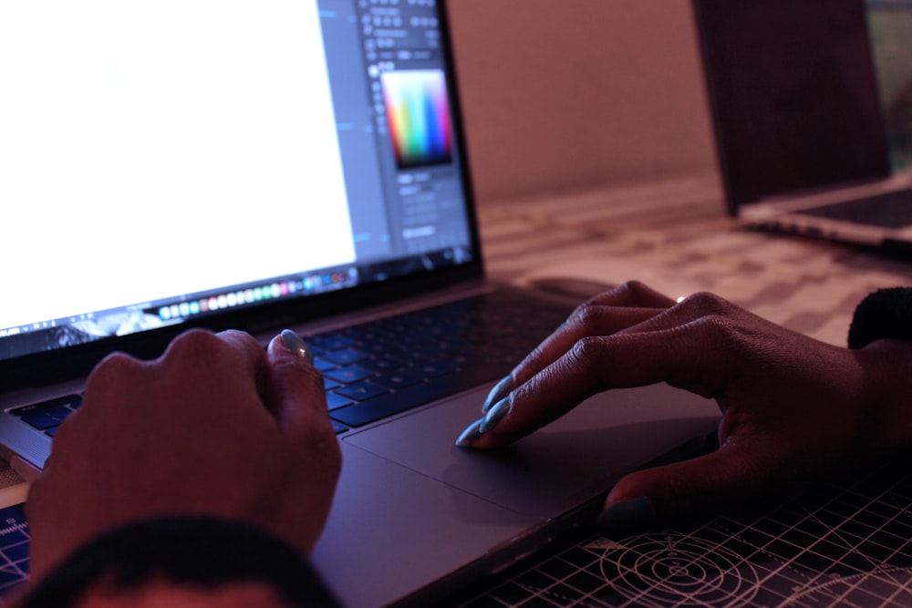 person using macbook pro on brown wooden table