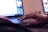 A person's hand is resting on the touchpad of a laptop, suggesting interaction with the device. The screen displays a bright interface, likely a graphic design or editing program. In the background, there is another computer screen visible, partially blurred.