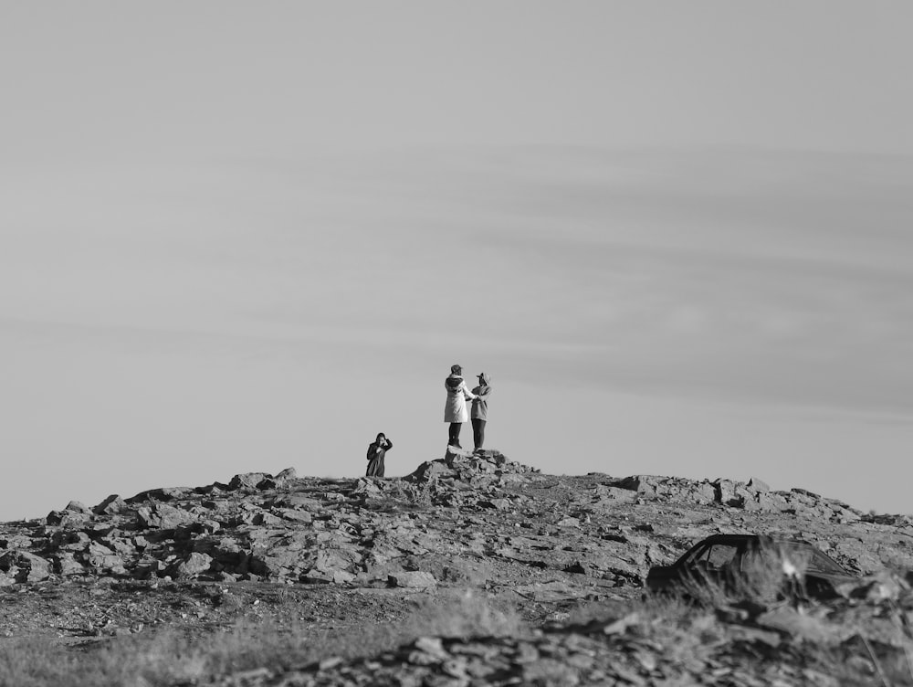 grayscale photo of 2 person standing on rock formation