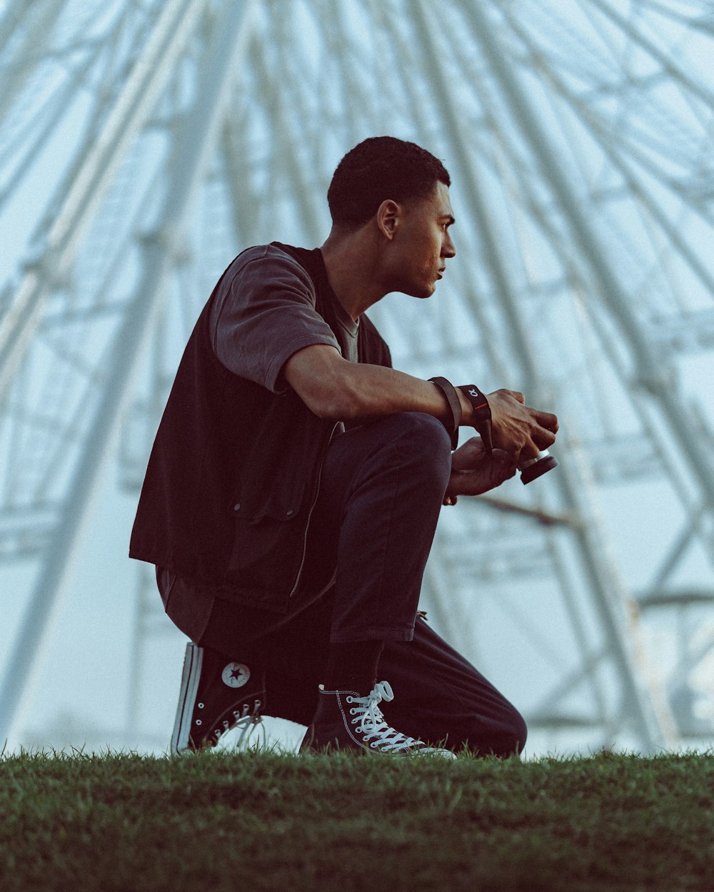 man in black t-shirt and black pants sitting on green grass field during daytime