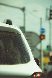 Close-up of a hand holding a traffic ticket with a car in the background.