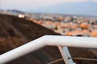 White PVC balcony railing with a city skyline in the background.