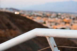 White PVC balcony railing with a city skyline in the background.