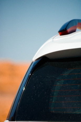 Close-up of a vehicle equipped with a compact telematics device under a bright sky.