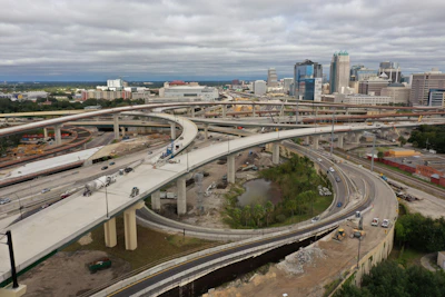 Wide aerial view of a highway toll road project under construction with machinery and workers.