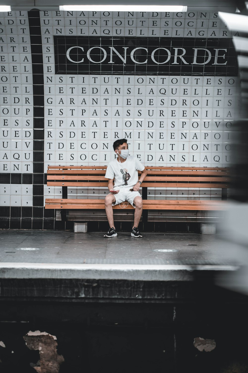 man in white t-shirt sitting on brown wooden bench