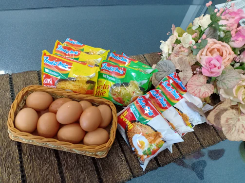 Close-up of vibrant Saudi Indomie noodle packets arranged with golden accents.